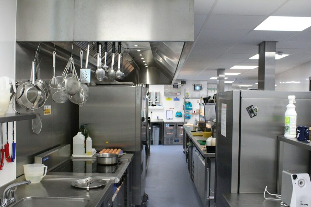Cucina professionale di ristorazione con piani di lavoro in acciaio inox e cappa di aspirazione, ambiente in cui si applica il piano HACCP