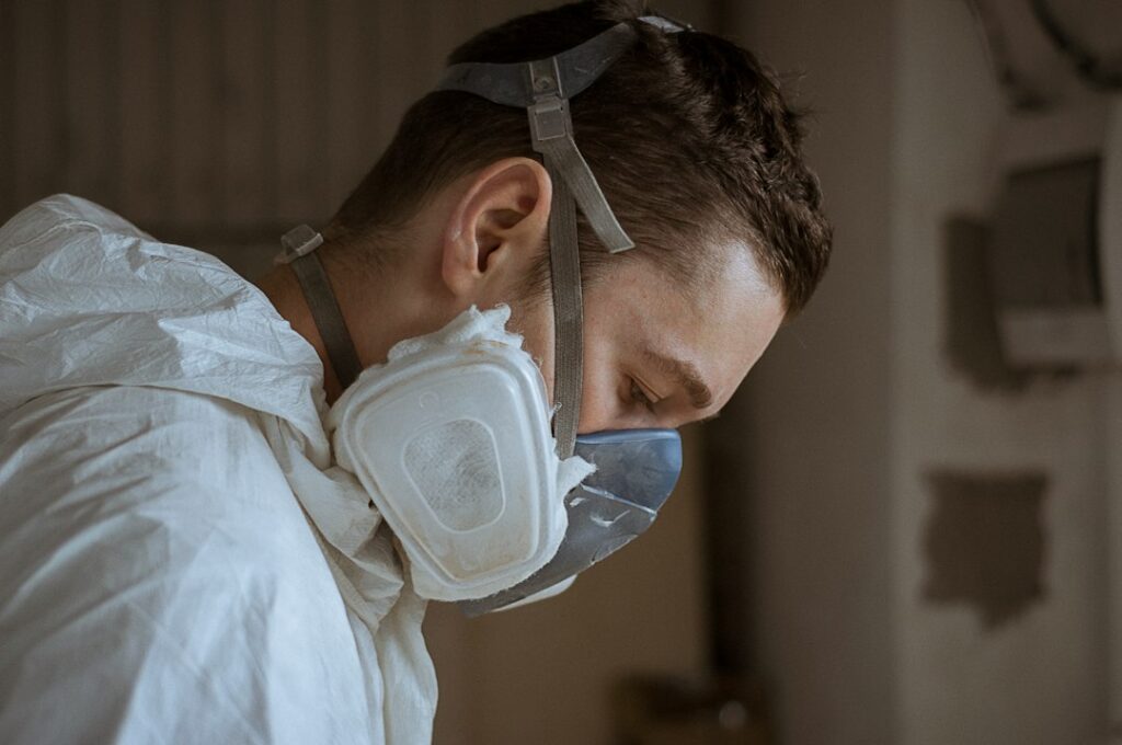 Lavoratore che indossa un respiratore per proteggersi dall'inalazione di fibre, prevenzione del carcinoma da amianto