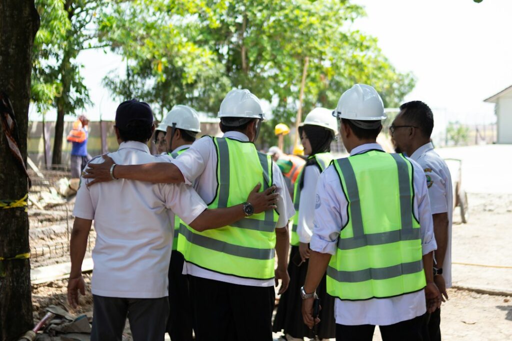 Gruppo di lavoratori con casco e gilet ad alta visibilità riuniti in cantiere, immagine per la giornata mondiale della salute e sicurezza sul lavoro
