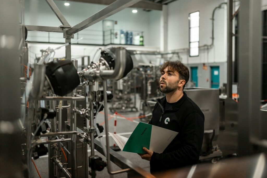 Tecnico con documentazione tecnica in mano verifica un impianto industriale, figura a cui rivolgersi per la valutazione acustica