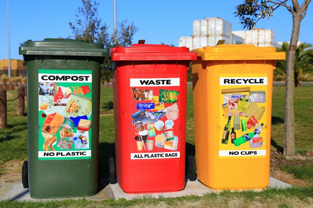 Tre contenitori colorati per la raccolta differenziata allineati, esempio di corretta gestione dei rifiuti