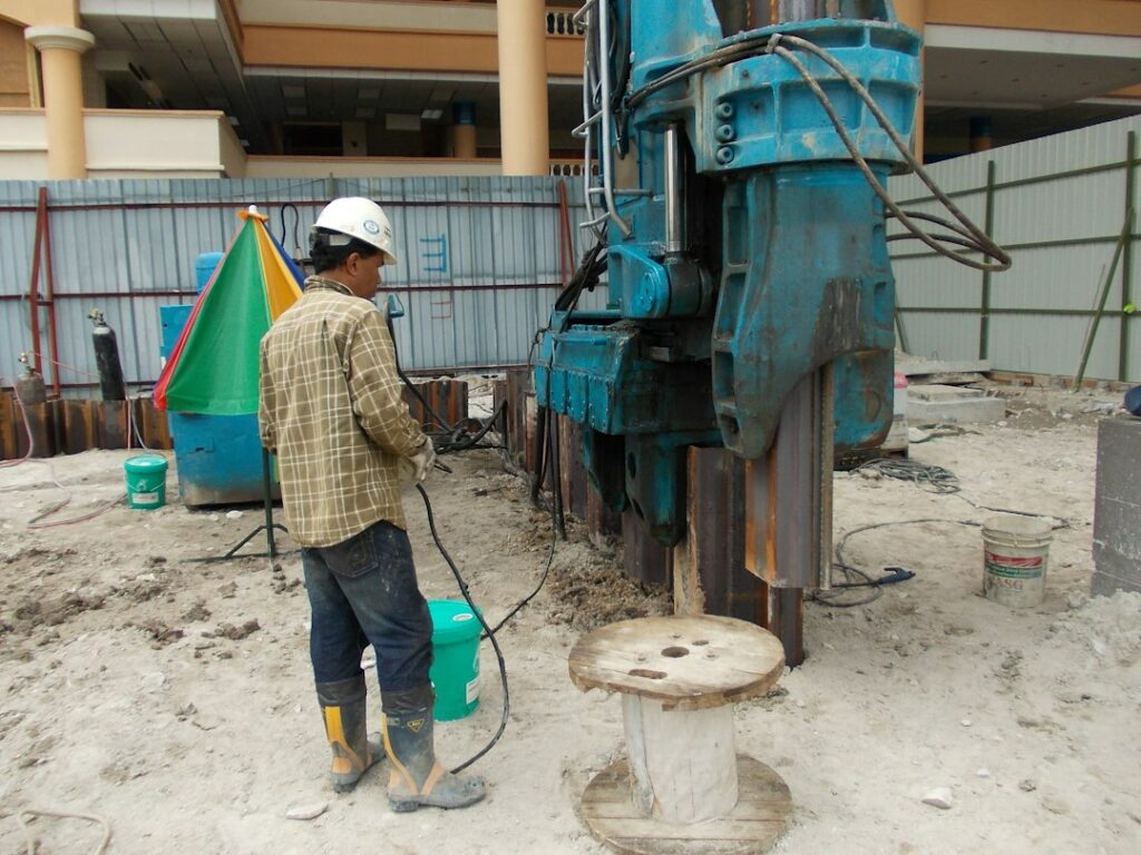 Macchina per l'infissione di palancole in cantiere, lavorazione che espone gli operatori al rischio da vibrazioni