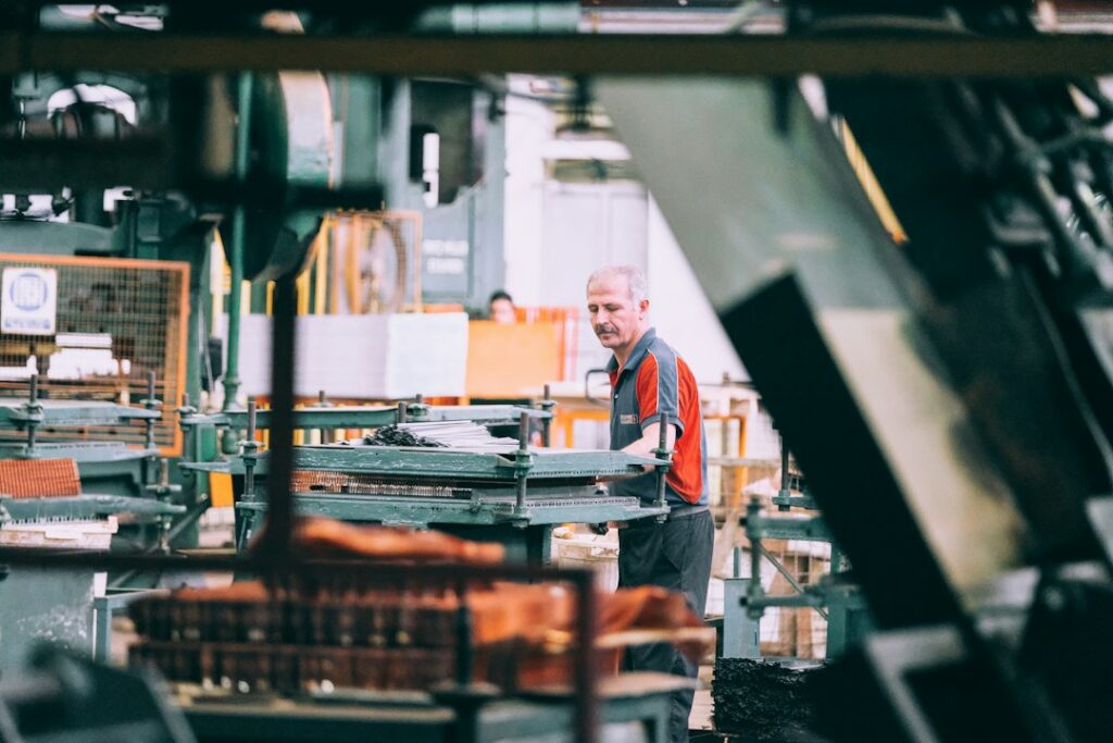 Operatore al lavoro su un macchinario industriale rumoroso, contesto tipico della valutazione di impatto acustico