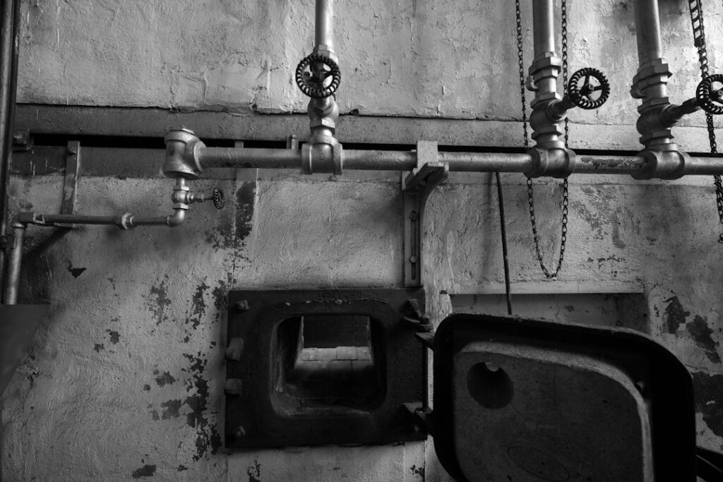 Tubazioni e valvole di una centrale termica sopra lo sportello di una caldaia, impianto da controllare per il rischio legionella