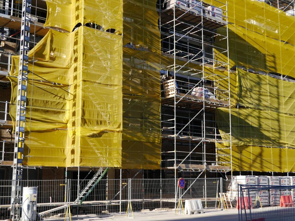 Ponteggio coperto da teli gialli su un piccolo cantiere edile residenziale, dove si applica la sicurezza nei cantieri