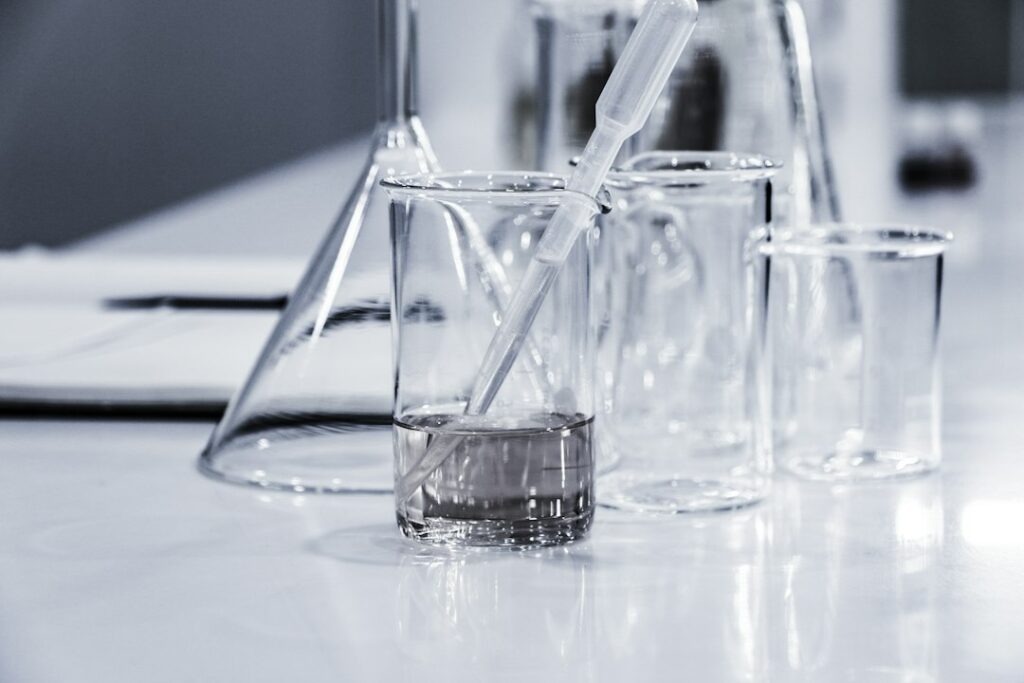 Tre becher di vetro trasparenti su un banco di laboratorio, usati per le analisi di caratterizzazione dei rifiuti