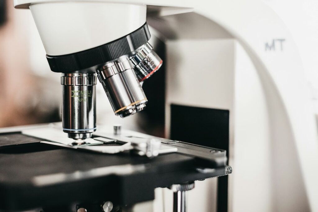 Microscopio ottico con obiettivi multipli sopra il piano portaoggetti, strumentazione del laboratorio analisi di igiene industriale