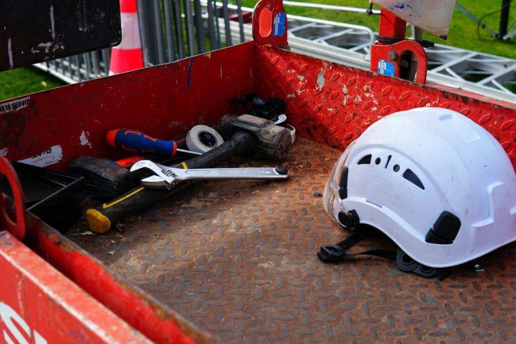Casco protettivo bianco e attrezzi da lavoro in una cassetta metallica rossa, dotazione per la sicurezza sul lavoro in azienda