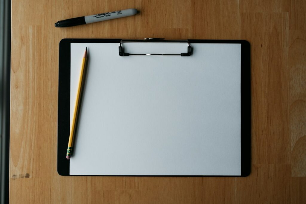 Clipboard con foglio, matita e penna su un piano di legno, strumenti per la valutazione dei rischi aziendale