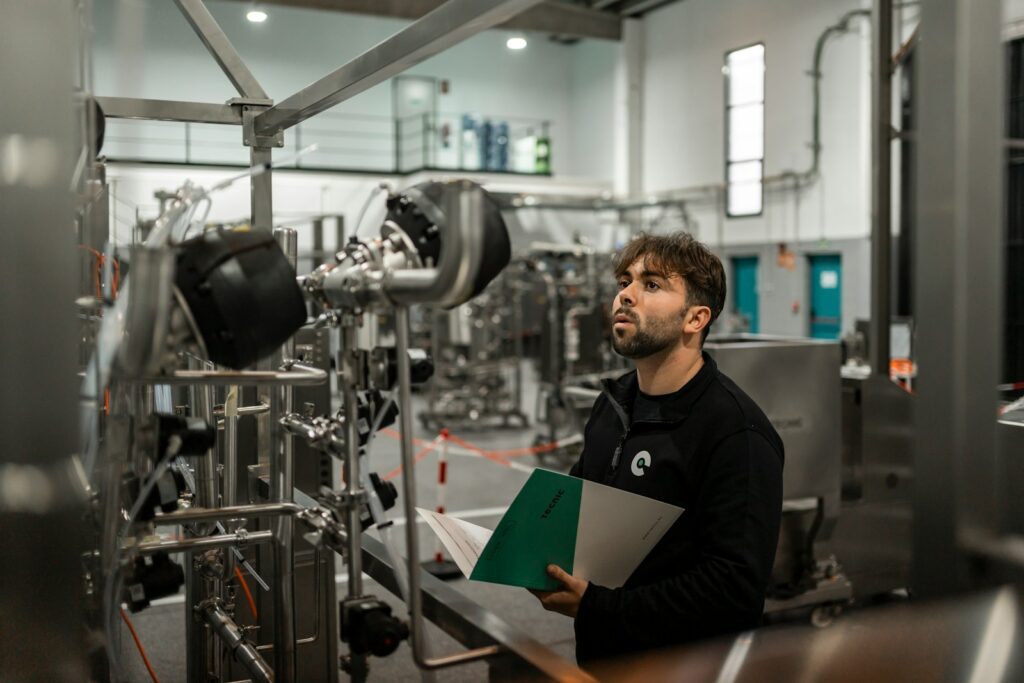 Tecnico con documentazione tecnica in mano verifica un impianto industriale, attività tipica di un sistema di gestione ISO