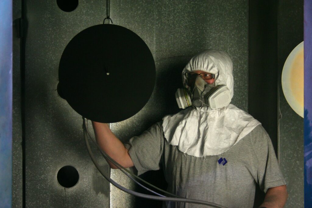 Operatore con tuta protettiva integrale e respiratore al lavoro in uno stabilimento, DPI previsti dalla normativa amianto