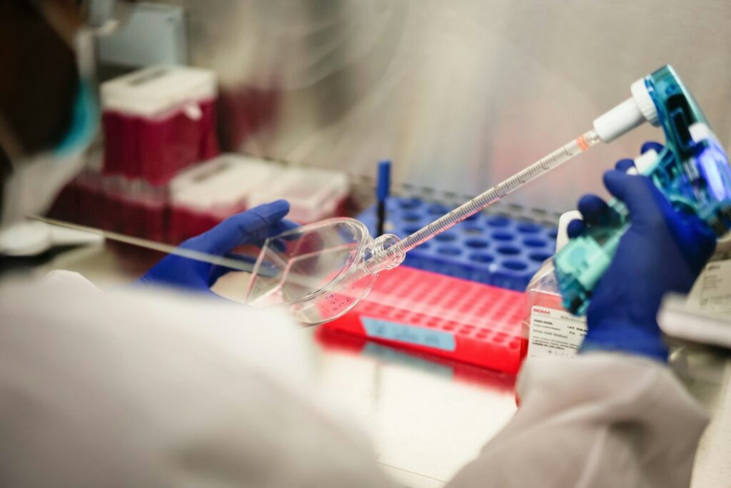 Ricercatore con guanti misura colture cellulari in laboratorio, contesto tipico del rischio biologico sul lavoro