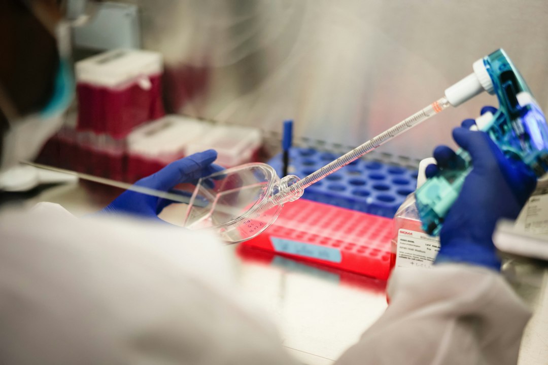 Ricercatore con guanti misura colture cellulari in laboratorio, contesto tipico del rischio biologico sul lavoro