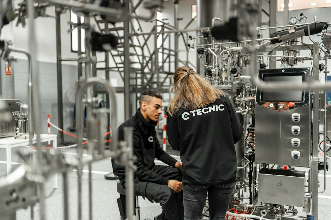 Due tecnici di imprese diverse controllano un impianto in acciaio in un locale tecnico, situazione tipica di interferenze da gestire nel DUVRI